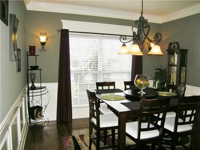 Formal dining room with wide crown molding, decorative window headers, chair rail, and picture framing. 