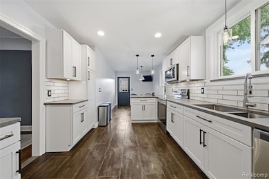 Kitchen featuring hanging light fixtures, appliances with stainless steel finishes, white cabinets, and recessed lighting