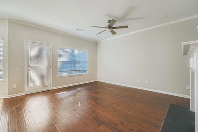 Empty room with dark wood-style floors, crown molding, plenty of natural light, and ceiling fan