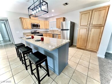 Kitchen featuring stainless steel appliances, light tile patterned flooring, a kitchen bar, pendant lighting, and recessed lighting