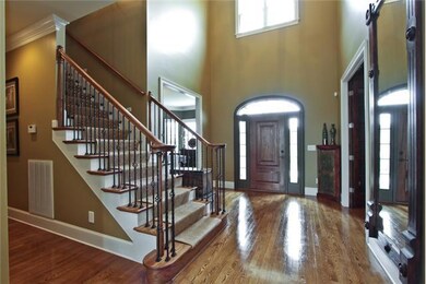 Large two story foyer with cat-walk and balcony above.  Beautiful hardwood step, ornate handrail and iron spindles.  Notice the custom wood moldings and pristine carpentry.