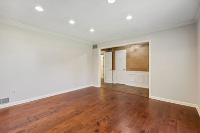 Empty room with hardwood / wood-style floors, crown molding, wainscoting, and recessed lighting
