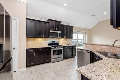 Beautiful kitchen with dark cabinetry, granite countertops, under cabinet lighting, and stainless steel appliances.