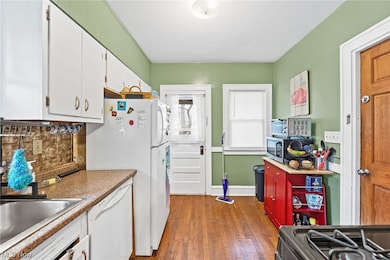 Up unit kitchen featuring white cabinets, hardwood / wood-style floors, and white appliance