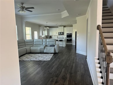 Living area with stairs, a ceiling fan, dark wood-style floors, crown molding, and baseboards