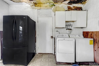 Laundry area with separate washer and dryer, cabinet space, and a textured wall