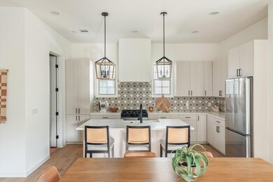 Kitchen with stainless steel appliances, decorative light fixtures, a breakfast bar, tasteful backsplash, and light wood-type flooring