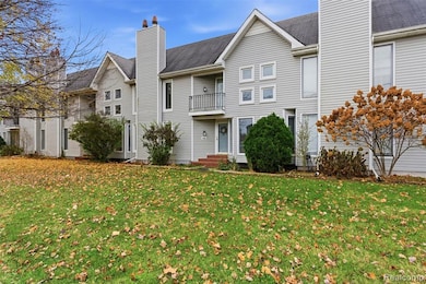 View of front of house with a chimney, a front lawn, a balcony, and a shingled roof