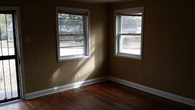 Spare room with dark wood-type flooring, wood walls, and ornamental molding
