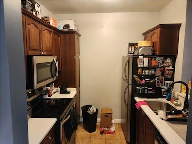 Kitchen with appliances with stainless steel finishes, light tile patterned flooring, and dark brown cabinetry