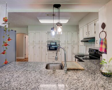 Kitchen with white cabinetry, black appliances, ha