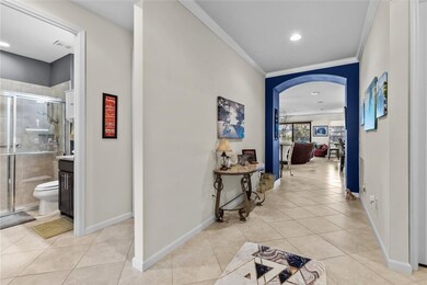 Hallway with arched walkways, light tile patterned floors, ornamental molding, and recessed lighting
