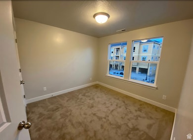 Spare room featuring carpet flooring and a textured ceiling