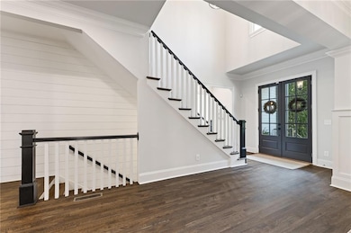Entryway with wood finished floors, stairs, ornamental molding, and baseboards