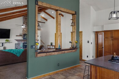 Kitchen featuring high vaulted ceiling, baseboards, beam ceiling, dark countertops, and a breakfast bar