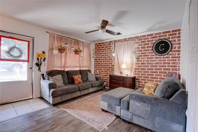 Living room with light wood-type flooring, brick w