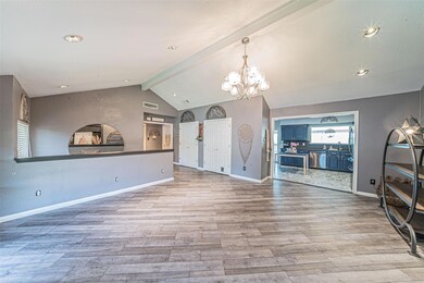 Unfurnished living room featuring a notable chandelier, sink, vaulted ceiling with beams, and light wood-type flooring