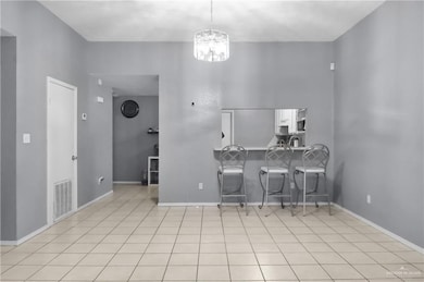 Kitchen featuring a breakfast bar, light tile patterned floors, pendant lighting, a chandelier, and a peninsula