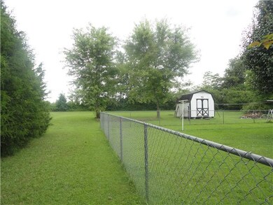 Back yard extends to tree line past fence.