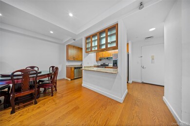 Kitchen with brown cabinetry, light wood-style floors, light stone counters, recessed lighting, and a peninsula
