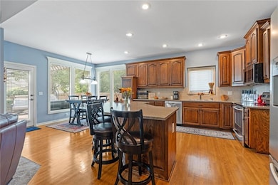 Kitchen with backsplash, brown cabinetry, appliances with stainless steel finishes, a kitchen island, and recessed lighting