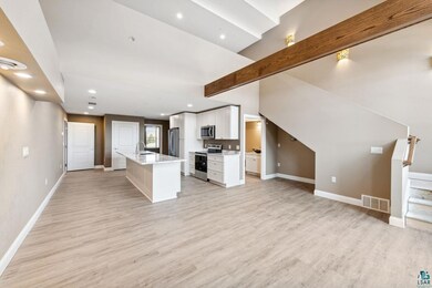 Unfurnished living room with sink, beam ceiling, and light wood-type flooring
