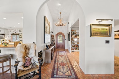 Foyer entrance with arched walkways, brick floors, a chandelier, and recessed lighting