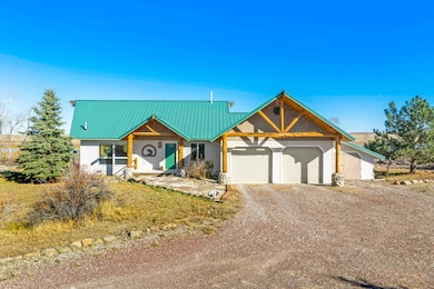 View of front of house featuring dirt driveway, a metal roof, covered porch, and an attached garage