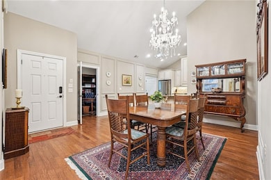 Dining space with wood finished floors, recessed lighting, a chandelier, high vaulted ceiling, and a decorative wall