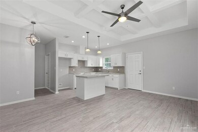 Kitchen featuring recessed lighting, light wood-style floors, tasteful backsplash, coffered ceiling, and white cabinetry