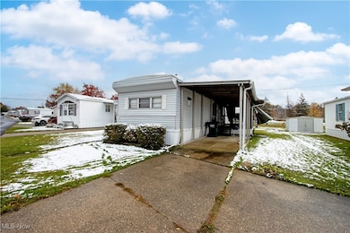 Snow covered property with driveway and an outdoor structure