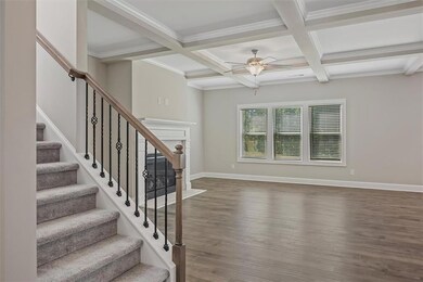 Stairway featuring a ceiling fan, beamed ceiling, wood finished floors, coffered ceiling, and ornamental molding