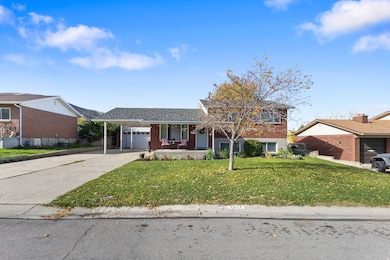 Split level home with a porch, brick siding, driveway, and a front yard