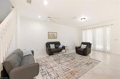 Living area with light tile patterned flooring, a ceiling fan, recessed lighting, and stairs