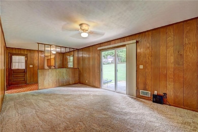 Unfurnished living room featuring carpet floors, a ceiling fan, wooden walls, and a textured ceiling