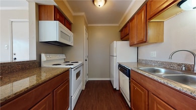 Kitchen with white appliances, dark wood-style flo