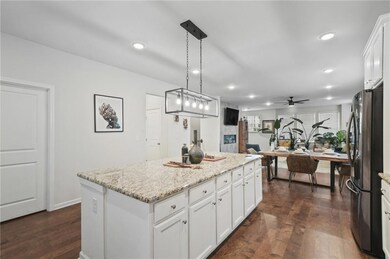 Kitchen featuring dark wood finished floors, freestanding refrigerator, a kitchen island, white cabinets, and recessed lighting