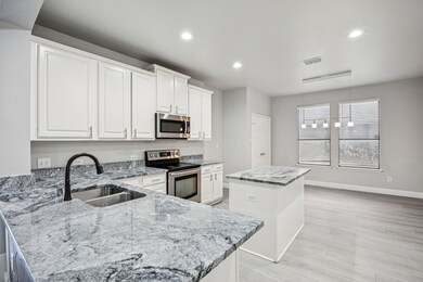 Kitchen featuring appliances with stainless steel finishes, light stone counters, a kitchen island, white cabinetry, and hanging light fixtures