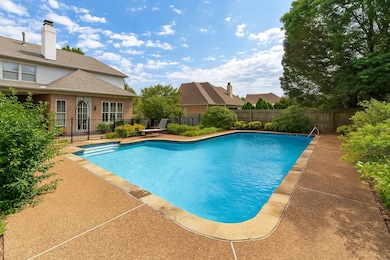 The shimmering in-ground pool takes center stage, while the covered patio provides a cozy lounge space complete with ceiling fans and ambient lighting. The outdoor kitchen—features a built-in grill and sleek cabinetry.