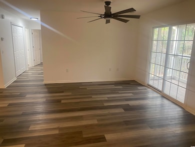 Spare room featuring ceiling fan, dark wood-type f