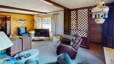 Living area featuring beam ceiling, wood walls, ca