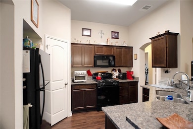 Kitchen with visible vents, a sink, dark brown cab