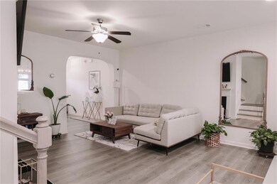 Living room featuring arched walkways, ceiling fan, wood finished floors, and stairs