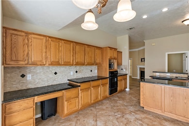 Kitchen featuring backsplash, brown cabinets, dark stone counters, black oven, and a textured ceiling