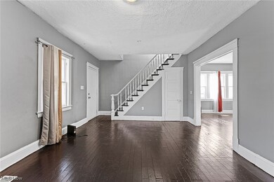 Entrance foyer with a textured ceiling and dark hardwood / wood-style flooring