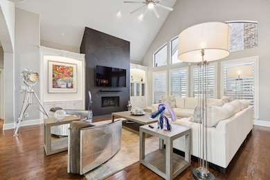 Living room with high vaulted ceiling, dark wood-style flooring, a large fireplace, and ceiling fan