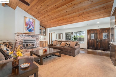 Living area featuring wood ceiling, a brick fireplace, high vaulted ceiling, light wood-style flooring, and ceiling fan
