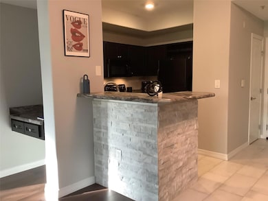 Bar featuring, refrigerator, black microwave, light tile tile floor, and baseboards