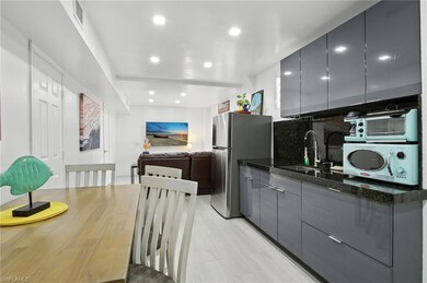 Kitchen featuring gray cabinets, open floor plan, freestanding refrigerator, backsplash, and recessed lighting