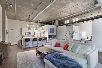 Living area with a barn door, dark wood-type flooring, and a high ceiling